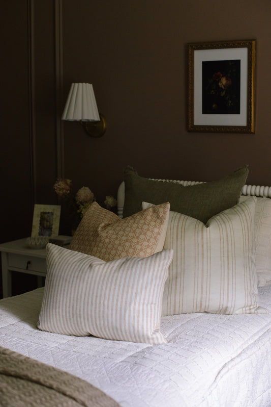 Bedroom with a bed featuring patterned and striped pillows, a lamp, and a framed picture on the wall.