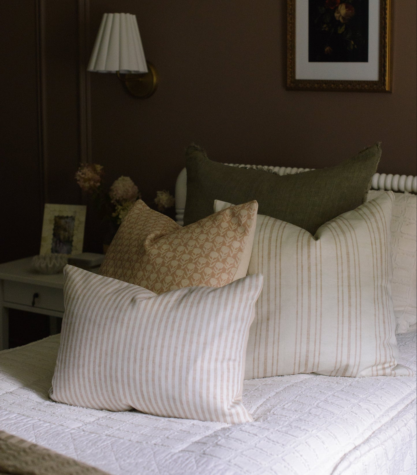 Bedroom with a bed featuring patterned and striped pillows, a lamp, and a framed picture on the wall.