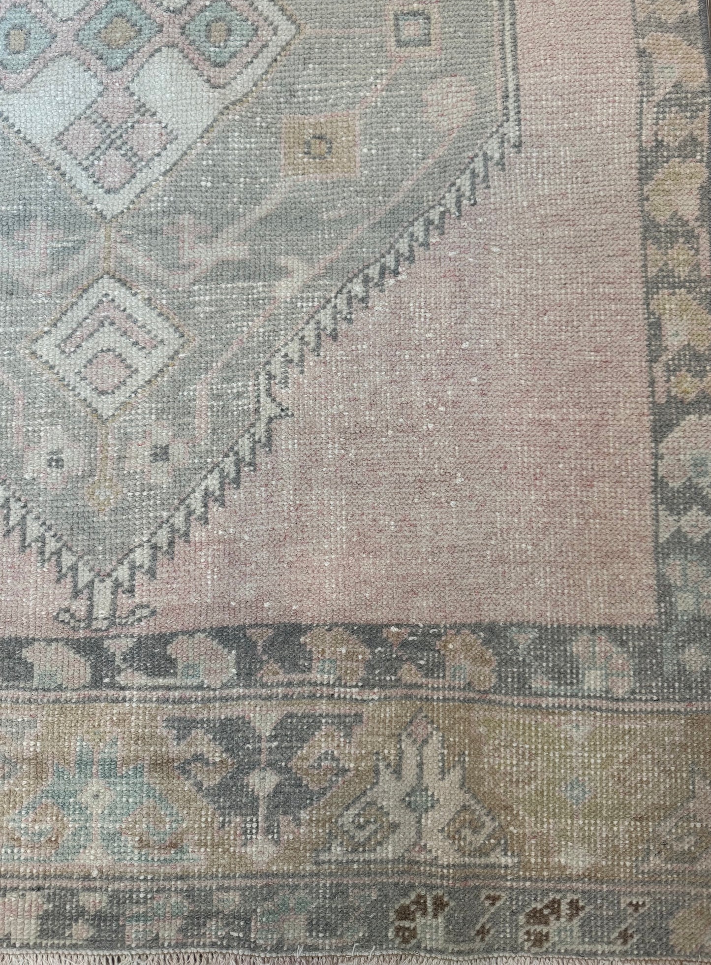 Close-up of a patterned rug with geometric designs in neutral colors.