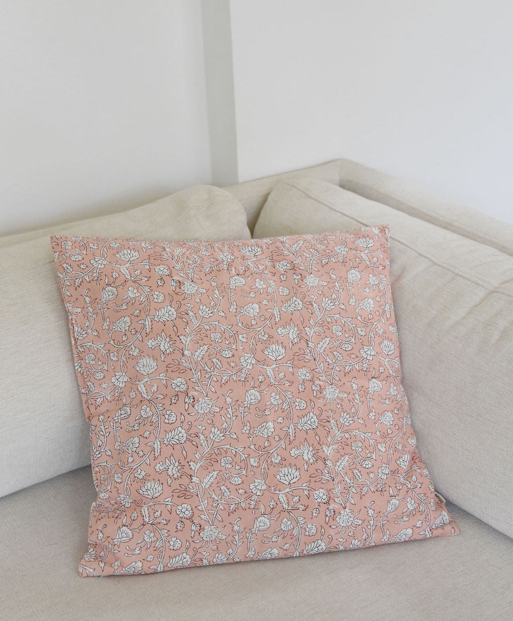 block print Floral-patterned pillow on a beige sofa against a white wall