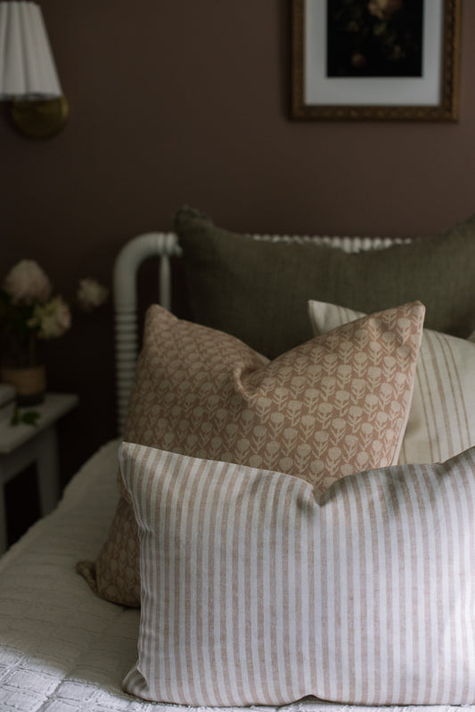 Decorative pillows on a bed with a dark wall and framed picture in the background