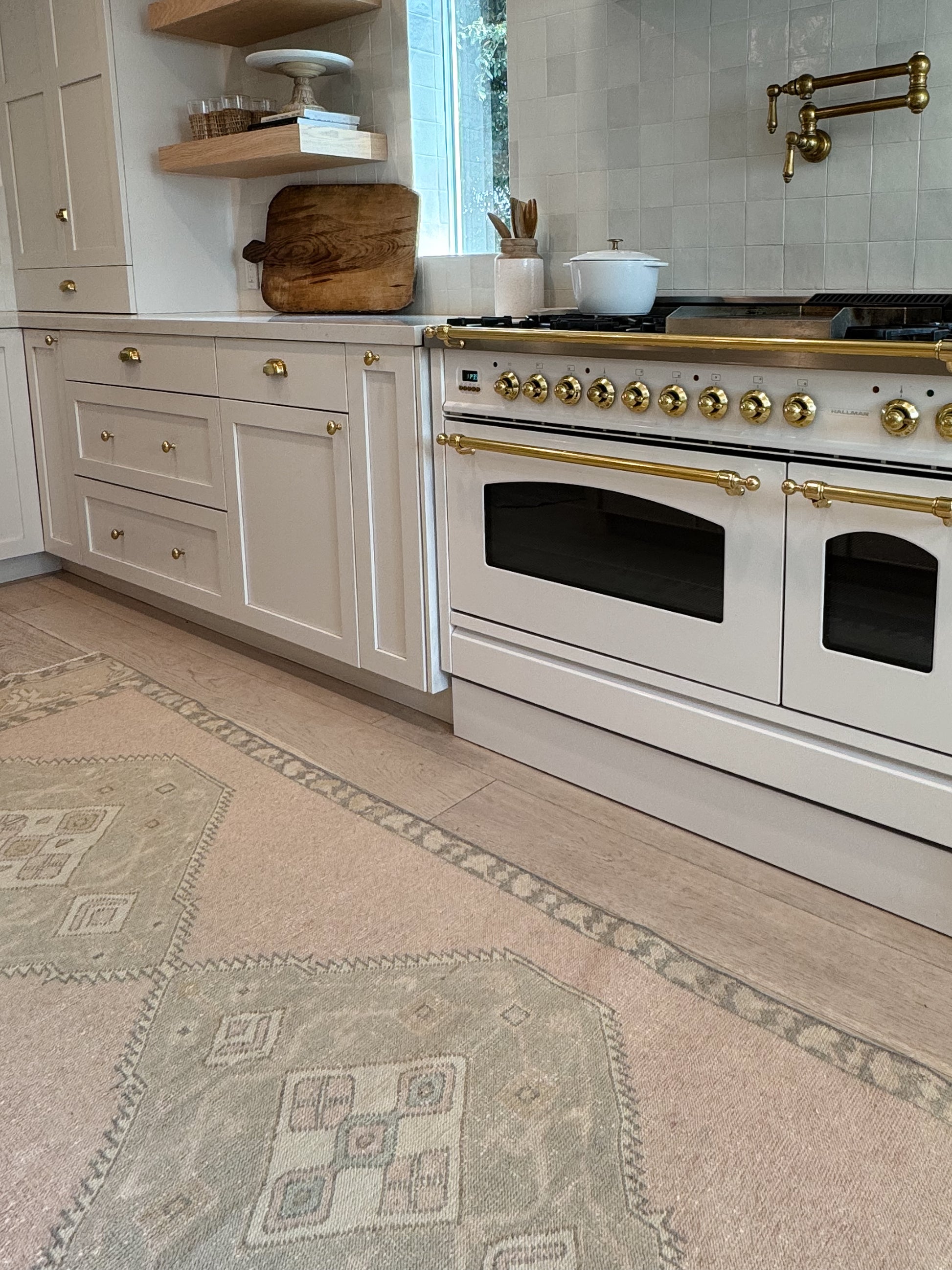 Kitchen with white stove and gold fixtures, patterned neutral vintage rug on floor