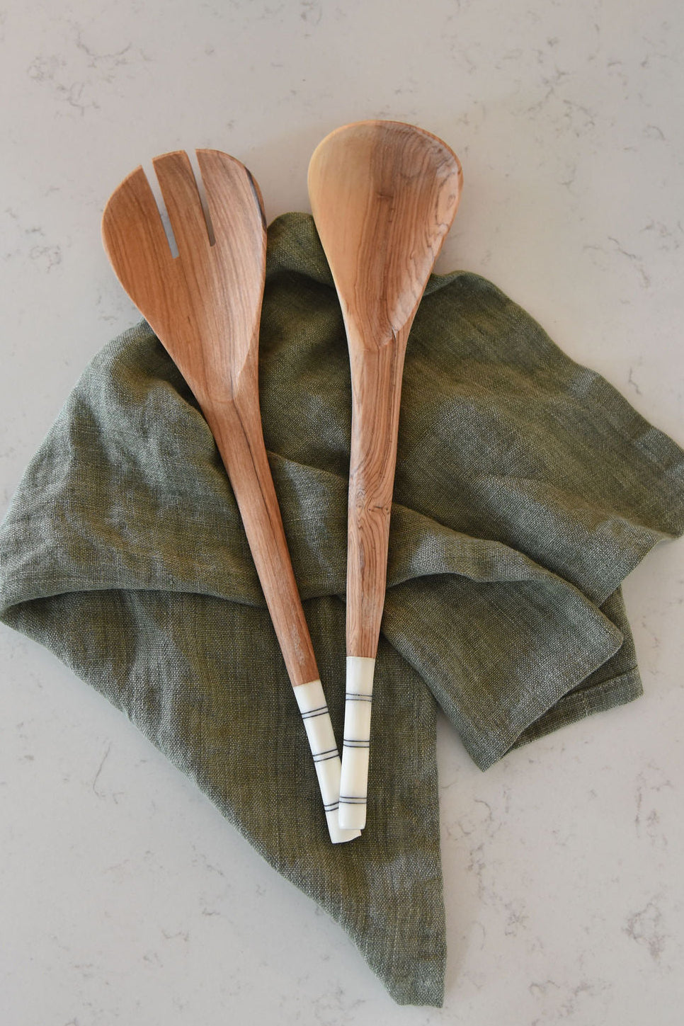 Two wooden spoons on a green linen towel with a light background