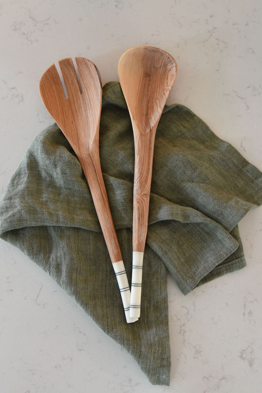 Two wooden spoons on a green linen towel with a light background