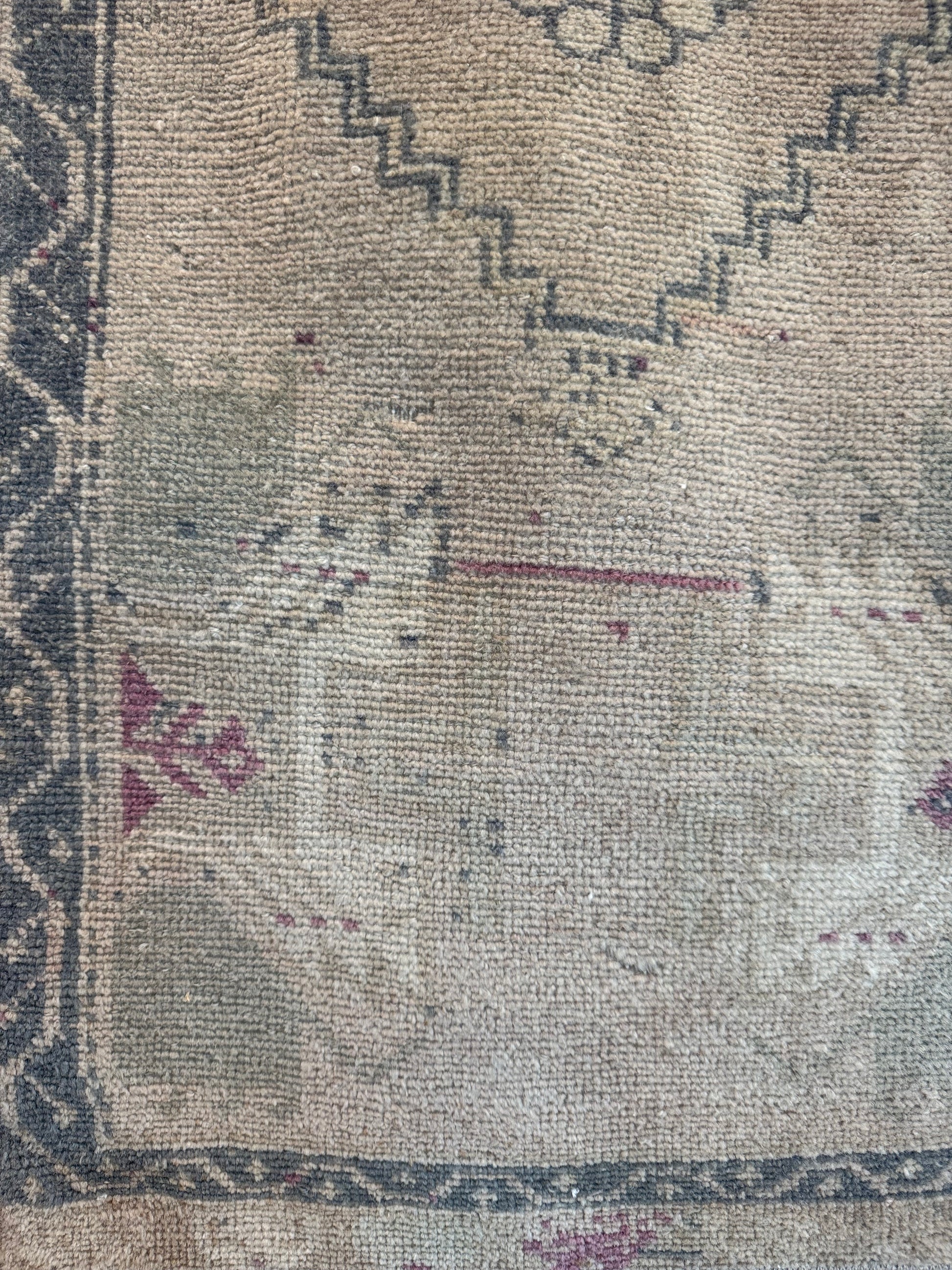 Close-up of a a neutral vintage turkish rug with blue and pink accents